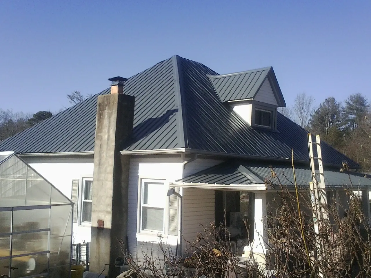Dark blue standing seam metal roof on a white farmhouse with dormer — Slate & Tile Roof Repair by Roofing Brothers in Forestburgh
