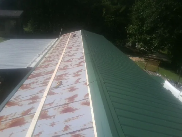 Old rusted panels beside newly installed green metal roofing — Wind Damage Roof Repair by Roofing Brothers in Forestburgh