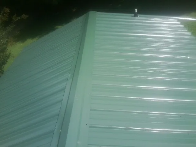 New green metal panels meeting at the ridge of a roof — Flat Roof Repair work by our crew in Forestburgh
