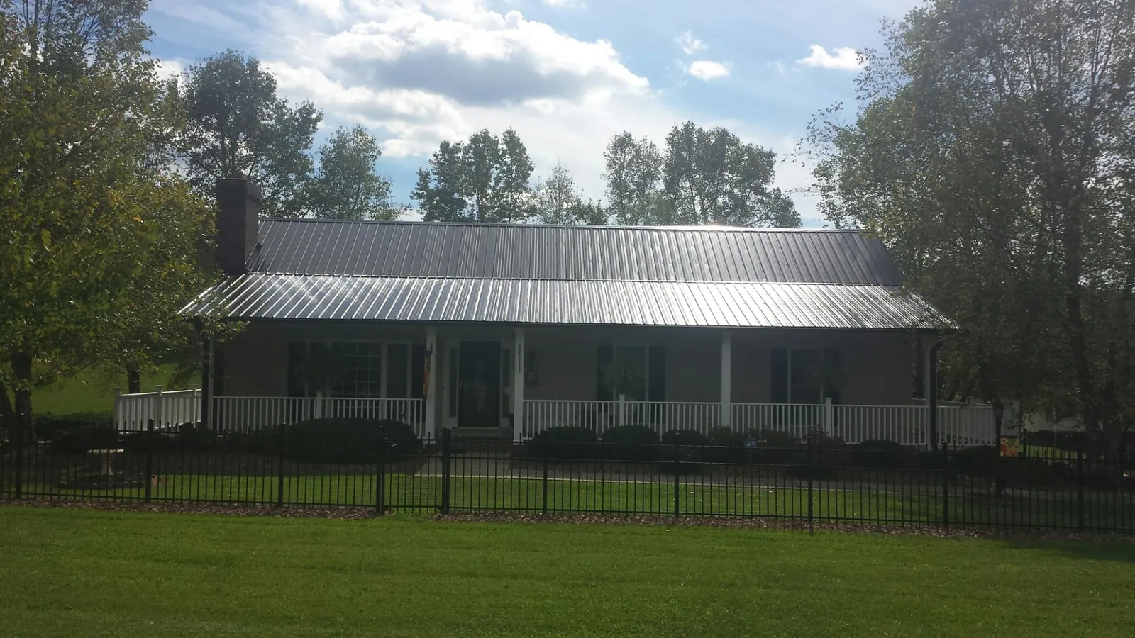 Gray metal roof on a brick ranch with a full width front porch — Gutter Guard Installation work by our crew in Forestburgh